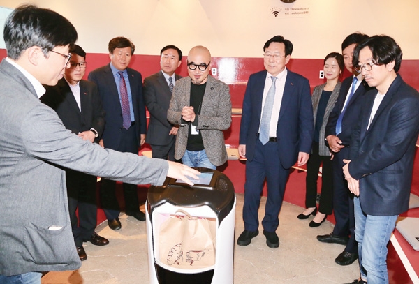 지난 25일 서울 송파구 우아한형제들 본사를 방문한 김기문 중기중앙회장(오른쪽 네번째)과 참석자들이 자율주행 배달로봇을 살펴보고 있다.