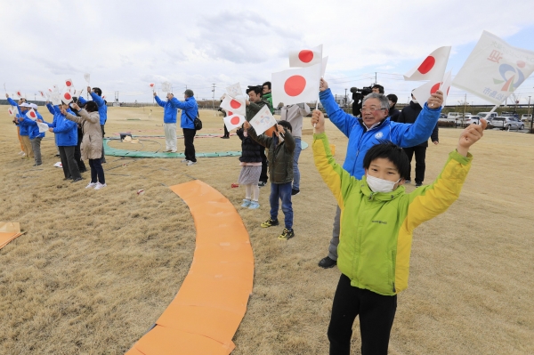 2020 도쿄올림픽 성화를 실은 특별수송기가 지난 20일 미야기현의 항공자위대 마쓰시마 기지에 착륙하자 지역 주민들이 일장기를 흔들며 환호하고 있다.