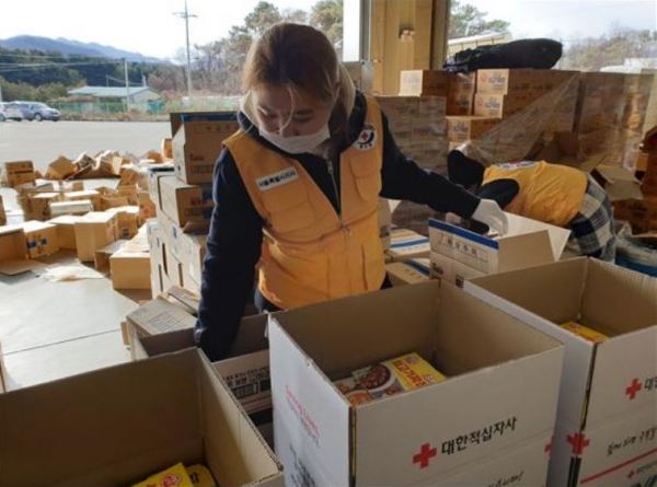 지난 23일, 경기도 용인시 물류창고에서 적십자 봉사원이 자가격리자에게 지원할 비상식량세트 1만1천세트를 제작하고 있다. [대한적십자사 제공]