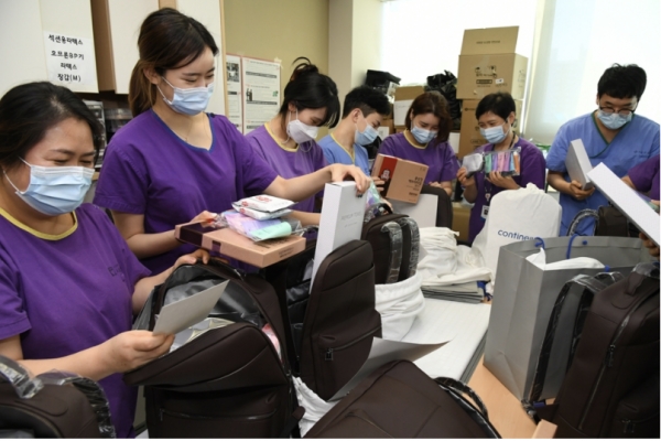 포스코가 9일 코로나19 환자를 치료하는 서울의료원 의료진에 응원 키트를 전달했다. 사진은 서울의료원 의료진들이 포스코가 친환경 가방에 담아 전달한 응원 키트를 살펴보고 있는 모습. [포스코 제공]