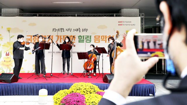 지난 12일 여의도 중소기업중앙회 문화마당에서 열린 ‘국화향기 가득한 힐링 음악회’에서 서울내셔널심포니오케스트라 현악 5중주가 연주하고 있다. 한 관객이 연주하는 모습을 찍고 있다. 	황정아 기자