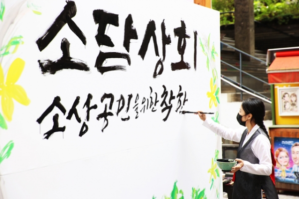 지난 15일 서울 인사동 쌈지길에서 열린 소상공인 플래그십 스토어 ‘소담상회’ 개장식에 참가한 예술인이 대형 붓글씨 연출을 통해 코로나19로 지친 소상공인을 위로하고 있다.