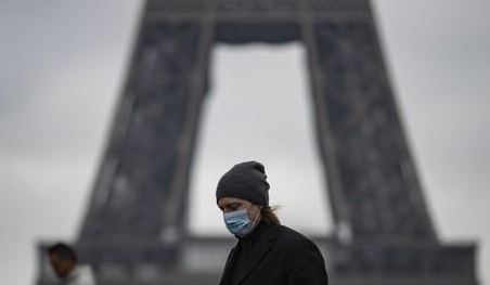마스크를 쓰고 파리 에펠탑 앞을 지나가는 시민