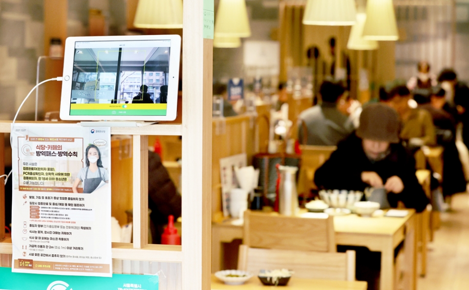 정부가 지난 1일 0시부터 식당·카페 등 11종 다중이용시설 전체에 대한 방역패스 적용을 일시 중단하기로 결정한 28일 서울의 한 음식점 입구에 설치된 발열체크 기계와 QR코드 확인 단말기 모습.