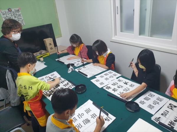 소명지역아동센터 아이들이 미술시간에 선생님의 지도를 받아 서예실습을 하고 있다.