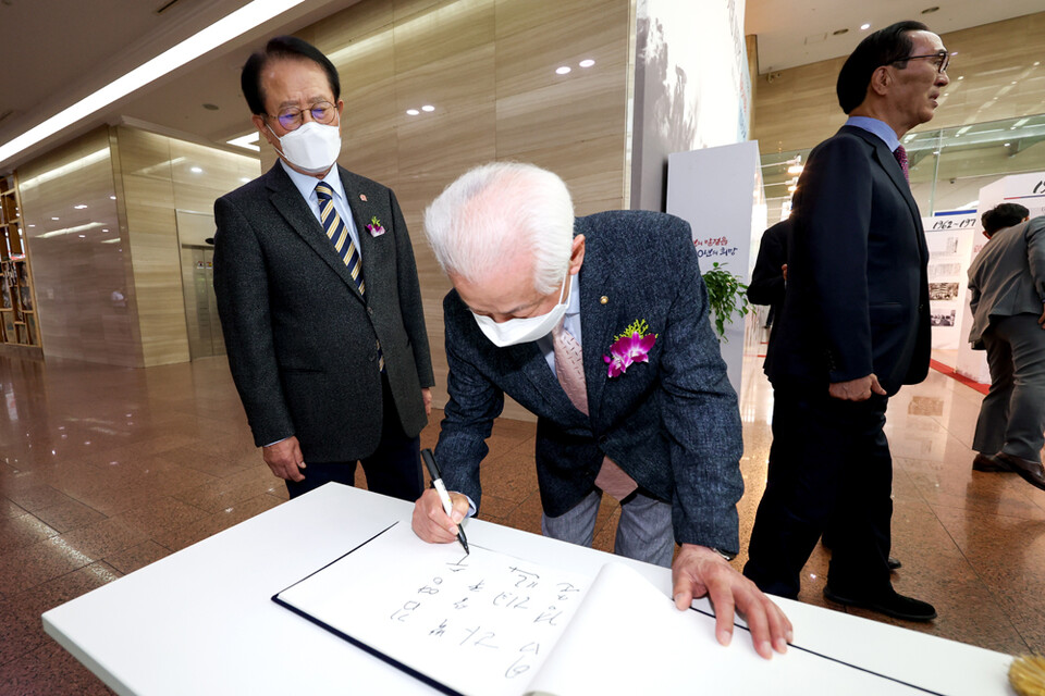 김영수 전 회장이 사진전 개막식에 참석해 방명록을 작성하고 있다.
