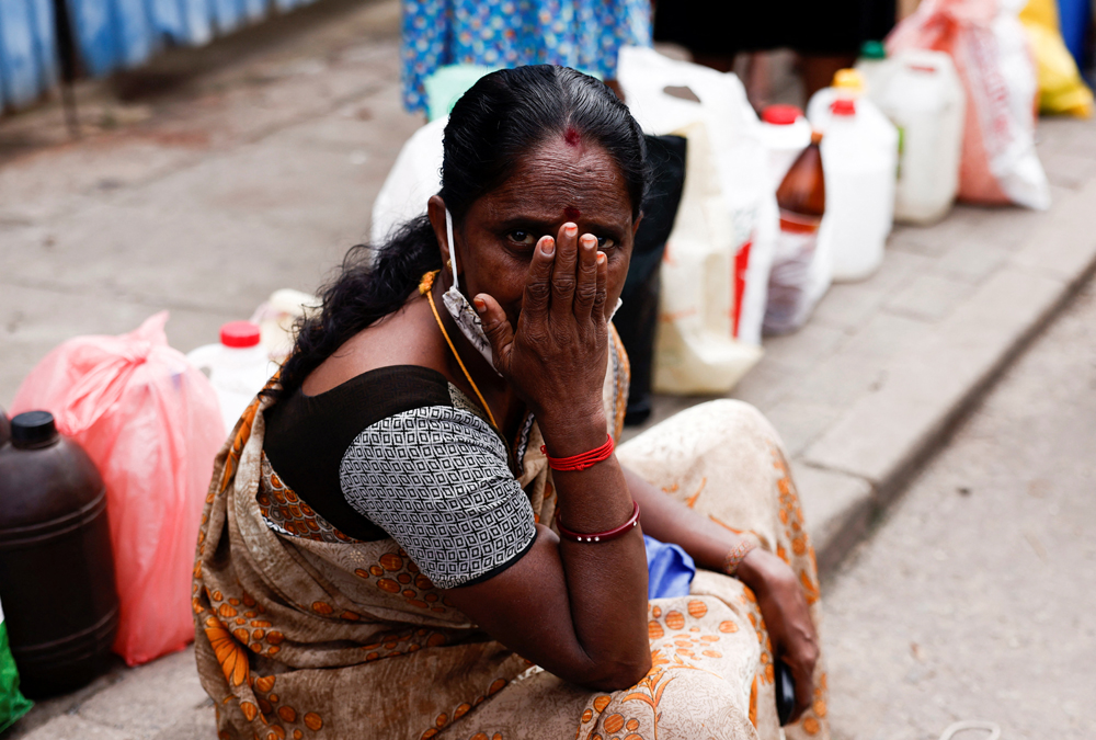 지난 17일(현지시간) 최악의 경제 위기를 겪고 있는 스리랑카 콜롬보에서 한 여성이 등유를 사기 위해 인도에 앉아 줄 서고 있다. 스리랑카는 지난 4월 일시적 채무불이행(디폴트)을 선언하고 현재 IMF와 협상 중이다.