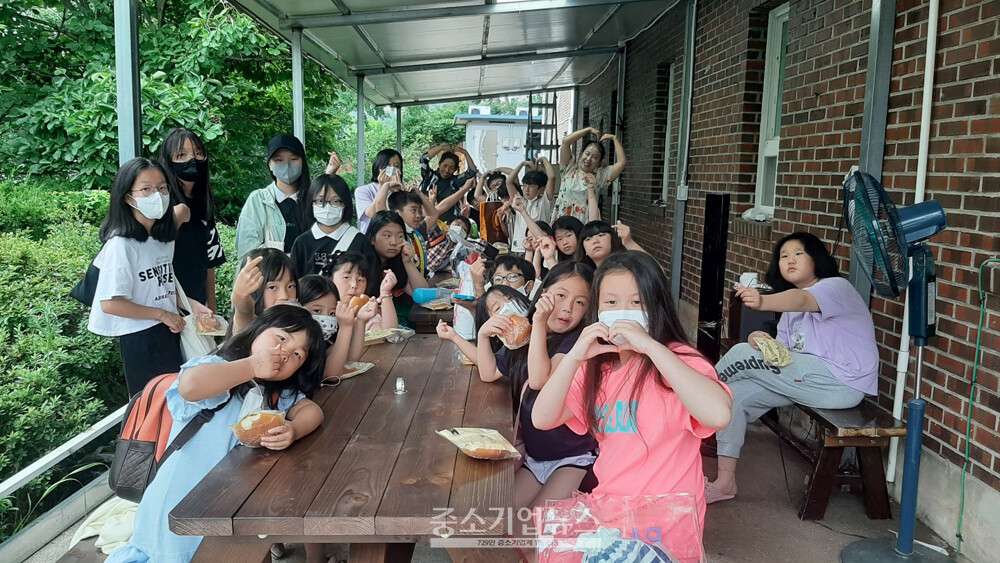 운호지역아동센터 아동들과 선생님들이 지난달 21일 한성넥스에서 기부한 테이블과 의자에서 간식을 먹으며 감사의 포즈를 취하고 있다.  