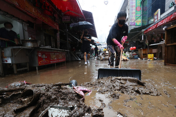 9일 폭우로 침수피해를 입은 서울 동작구 남성사계시장의 한 상인이 물과 쓰레기를 쓸어내고 있다. ⓒ연합
