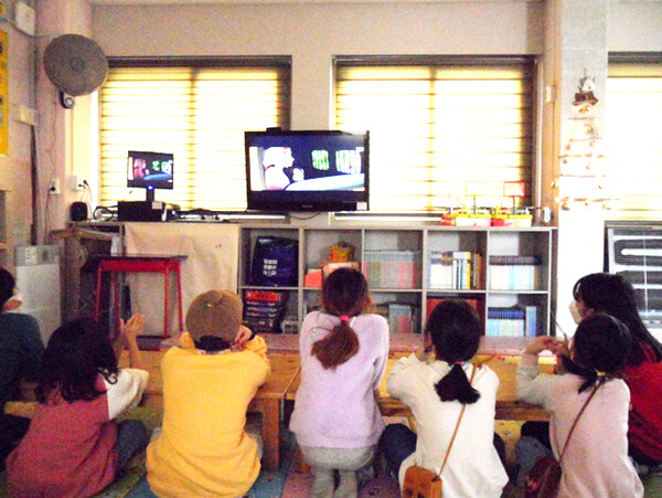 새 컴퓨터와 빔프로젝터가 필요한 푸른꿈지역아동센터의 아동들이 낡은 컴퓨터와 연결돼 중간 중간 화면이 멈추는 42인치 TV를 통해 애니메이션을 감상하고 있다.